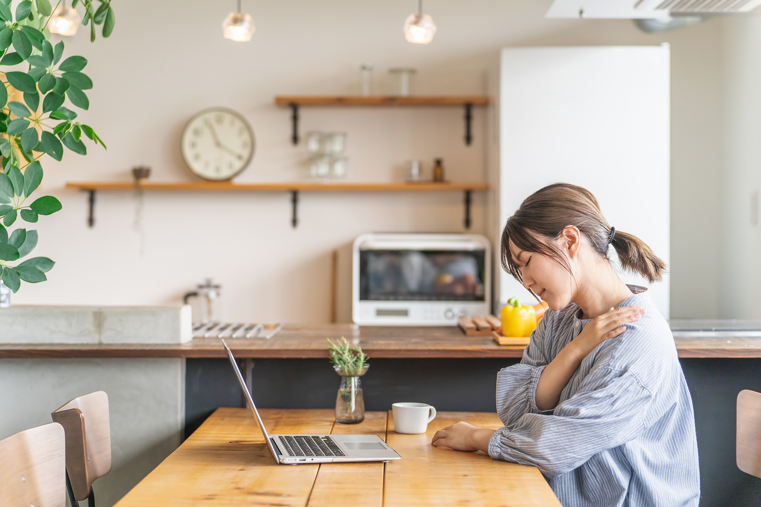 デスクワーク中の姿勢不良によって首や肩に負担がかかるイメージ